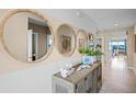 Bright entryway with coastal accents including round mirrors, woven buffet table, and neutral wall colors at 4946 Foxglove Cir, Lakeland, FL 33811