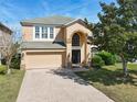 Inviting two-story home featuring a brick driveway, attached two-car garage, and an arched entryway at 643 Willett Dr E, Winter Garden, FL 34787