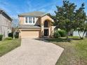 Inviting two-story home featuring a brick driveway, attached two-car garage, and an arched entryway at 643 Willett Dr E, Winter Garden, FL 34787