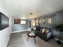 Inviting living room with gray walls, wood-look floors, a comfortable sofa, and seamless transition to the kitchen at 1246 Rhodes Ct, Orlando, FL 32808