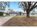 Lovely home with a lush front yard, mature tree providing shade, and a two-car garage at 205 Lori Ct, Umatilla, FL 32784