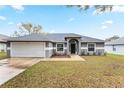 Inviting single-story residence featuring a well-manicured front lawn, a two-car garage, and a covered entryway at 205 Lori Ct, Umatilla, FL 32784