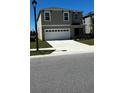 Two-story home with a two-car garage featuring a driveway and green space at 2597 Shamrock St, Tavares, FL 32778