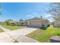 Inviting single-story home featuring a well-maintained lawn and a paved driveway leading to an attached two-car garage at 323 Shadow Oak Dr, Casselberry, FL 32707