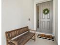 Cozy front porch featuring a wooden bench, a gray front door with glass and a wreath at 4418 Lions Gate Ave, Clermont, FL 34711