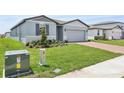Single-story home with a well-kept lawn and a brick driveway leading to a two-car garage at 4544 Windy Oak Way, St Cloud, FL 34772