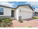 Home features a two-car garage, stone accents, and brick-paved driveway, complemented by lush landscaping at 4550 Windy Oak Way, St Cloud, FL 34772