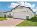 New home showcases two-car garage, stone accents, dark roof, exterior lights, and paved driveway at 4550 Windy Oak Way, St Cloud, FL 34772