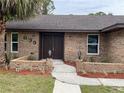 Inviting brick home with a well-manicured lawn, walkway, and beautiful double-door entrance at 635 Malaga Ave, Deltona, FL 32725