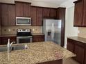 Spacious kitchen featuring dark wood cabinets, granite countertops, and stainless steel appliances at 8521 Vedder Ln, Orlando, FL 32832