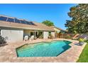 Backyard pool and patio features a solar-paneled roof for energy efficiency at 12712 Forestedge Cir, Orlando, FL 32828