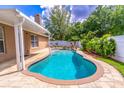 Backyard pool with waterfall feature, surrounded by brick pavers and lush tropical landscaping at 1272 Mount Logan Dr, Apopka, FL 32712