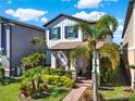 Beautiful two-story home with manicured lawn, palm trees, stone accents, and a brick pathway leading to the covered porch at 17055 Wynford Ln, Winter Garden, FL 34787