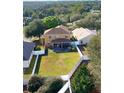 Aerial view of a large backyard with a covered patio and white picket fence at 25012 Chipshot Ct, Sorrento, FL 32776
