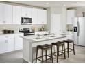Modern kitchen features white cabinets, stainless steel appliances, an island with breakfast bar seating at 305 Castle Dr, Lake Alfred, FL 33850