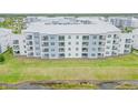 Exterior of a large condo building features white and blue facade and multiple balconies with green space at 3121 Paradox Cir # 307, Kissimmee, FL 34746