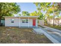 Cozy single-story home featuring a red front door, covered porch, and a charming landscape at 616 Conroy St, Orlando, FL 32805