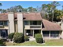 Rear exterior of the townhome featuring a covered patio, second story balcony, and lush landscaping at 1886 Saint Andrews Pl # 1886, Longwood, FL 32779