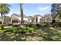 Elegant home with a side-entry garage, well-manicured lawn, lush landscaping, and mature trees at 25603 High Hampton Cir, Sorrento, FL 32776