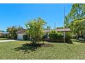 Single-story home with a stone accent wall, a green lawn, and mature landscaping at 412 Short Dr, Poinciana, FL 34759