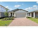 Charming single-story home with a brick driveway, light-colored exterior, and a two-car garage on a sunny day at 4973 Kaia Ave, Winter Haven, FL 33884
