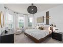 Sunlit main bedroom featuring a stylish woven light fixture, neutral palette, and a cozy seating area at 6017 Wildline Dr, St Cloud, FL 34771