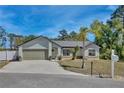 Inviting single-story home with a well-kept lawn, mature tree, and a paved driveway leading to an attached garage at 209 Roman Ct, Deltona, FL 32738