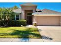 Inviting single-Gathering home featuring a well-manicured lawn, mature landscaping, and an attached two-car garage at 2519 Cypress Trace Cir, Orlando, FL 32825
