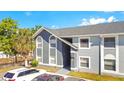 A two-story condo with distinctive architectural elements is surrounded by lush green trees and parked cars at 4314 Pershing Pointe Pl # 4, Orlando, FL 32822