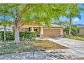 Inviting single-story home featuring a manicured lawn, two-car garage, and a charming, covered entryway at 5910 Windsong Oak Dr, Leesburg, FL 34748