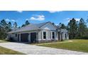 Side view of a house showing an attached two-car garage, stone accents, a metal roof, and a paved driveway at 947 Ferne Dr, Longwood, FL 32779