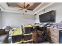Cluttered living room features gray walls, a tray ceiling, a ceiling fan, and a large TV at 1233 Bramley Ln, Deland, FL 32720