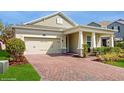 Inviting home featuring a two-car garage, brick driveway, and covered porch at 14345 Wabasso Loop, Winter Garden, FL 34787