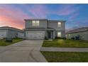 Charming two-story home features a two-car garage, manicured lawn, and a welcoming front entrance at dusk at 1506 Finnigan Cir, Haines City, FL 33844