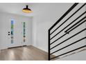 Bright foyer features a modern front door, light wood flooring, and black metal staircase railing at 1602 Park Lake St # 2, Orlando, FL 32803