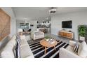 Bright living room with a white sofa, chairs, and a striped rug, adjacent to the dining area and modern kitchen at 2936 Woodcrest Ln, Lakeland, FL 33805