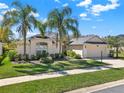 Well-manicured home exterior showcasing lush landscaping, a two-car garage, and a beautiful lawn at 3624 Belle Rose Dr, Leesburg, FL 34748