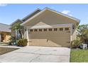 Beige single-Gathering home featuring a two-car garage, manicured landscape, and a cozy, welcoming ambiance at 459 Tivoli Cir, Davenport, FL 33837