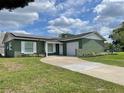 Charming, green single-story home featuring a welcoming front lawn, a driveway, and solar panels on the roof at 714 West Ct, Longwood, FL 32750