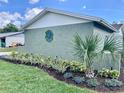Landscaped side of the home features a textured exterior, garden beds with fresh mulch, and small palm trees at 714 West Ct, Longwood, FL 32750
