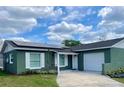 Charming green single-story home featuring a welcoming front lawn, a driveway, and solar panels on the roof at 714 West Ct, Longwood, FL 32750