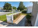 A sidewalk and manicured yard of the property featuring mature trees, shrubs, and a decorative picket fence at 8201 Se 169Th Palownia Loop, The Villages, FL 32162