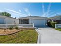 Inviting single-story home featuring a manicured lawn, white picket fence, and an attached two-car garage at 8233 Se 169Th Palownia Loop, The Villages, FL 32162