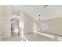 Bright living room with high ceilings, a modern chandelier, arched doorway, and lots of natural light at 1110 Stoneham Dr, Groveland, FL 34736