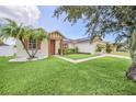 Attractive single-story home features a well-manicured lawn, palm trees, and covered entryway at 14815 Tullamore Loop, Winter Garden, FL 34787