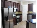 Well-lit kitchen features stainless steel appliances, dark cabinetry and stone countertops at 4964 Luge Ln, Orlando, FL 32839