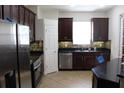 A kitchen shows stainless steel appliances, dark cabinetry and tile flooring at 4964 Luge Ln, Orlando, FL 32839