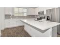 Modern kitchen featuring white cabinets, stainless steel appliances, and a spacious quartz countertop island at 6633 Calamondin Dr, Winter Garden, FL 34787