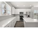 Modern kitchen featuring white cabinets, stainless steel appliances, stone countertops, and hardwood flooring at 6633 Calamondin Dr, Winter Garden, FL 34787