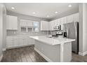 Modern kitchen featuring white cabinets, stainless steel appliances, stone countertops, and hardwood flooring at 6633 Calamondin Dr, Winter Garden, FL 34787
